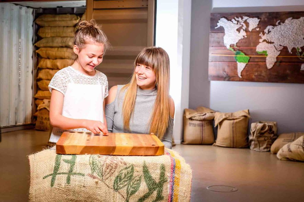 Lachende Gäste im Chocoversum mit Kakaobohnen vor Weltkarte