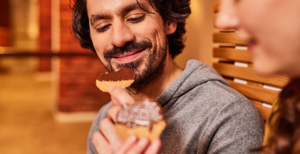 Lächelnder Mann verkostet Schokolade mit Waffel
